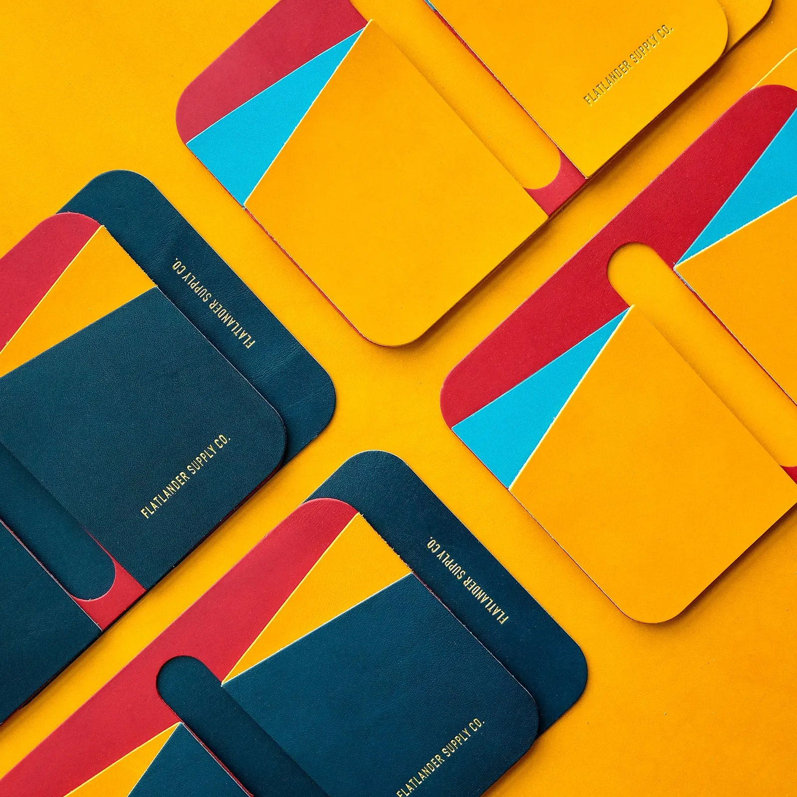 Navy card sleeves with red and cyan contrast panels scattered across a yellow leather hide
