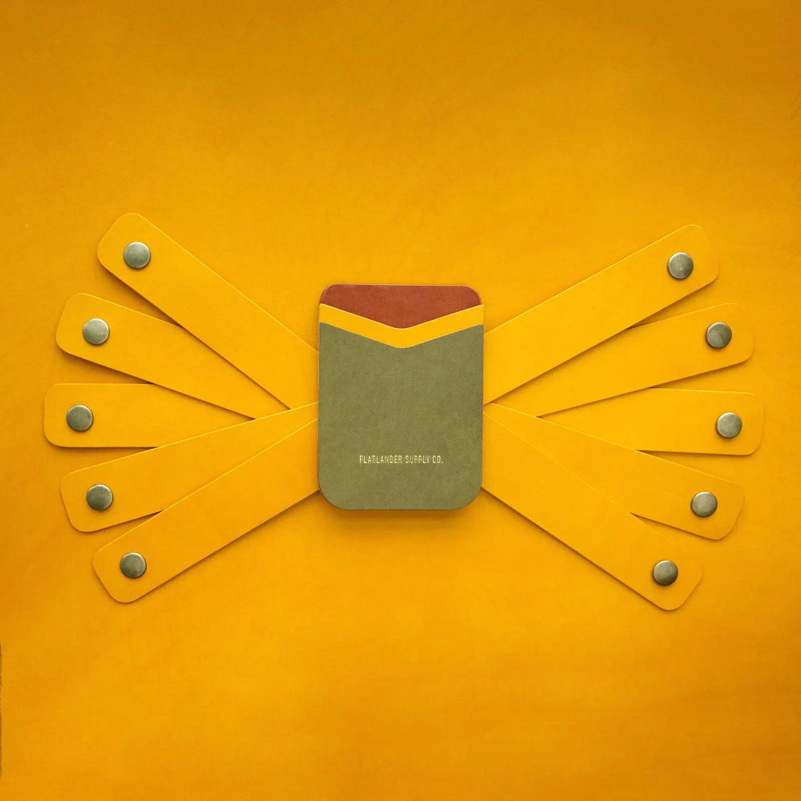 Yellow leather straps fanned out from a card sleeve with brass snaps set into each strap